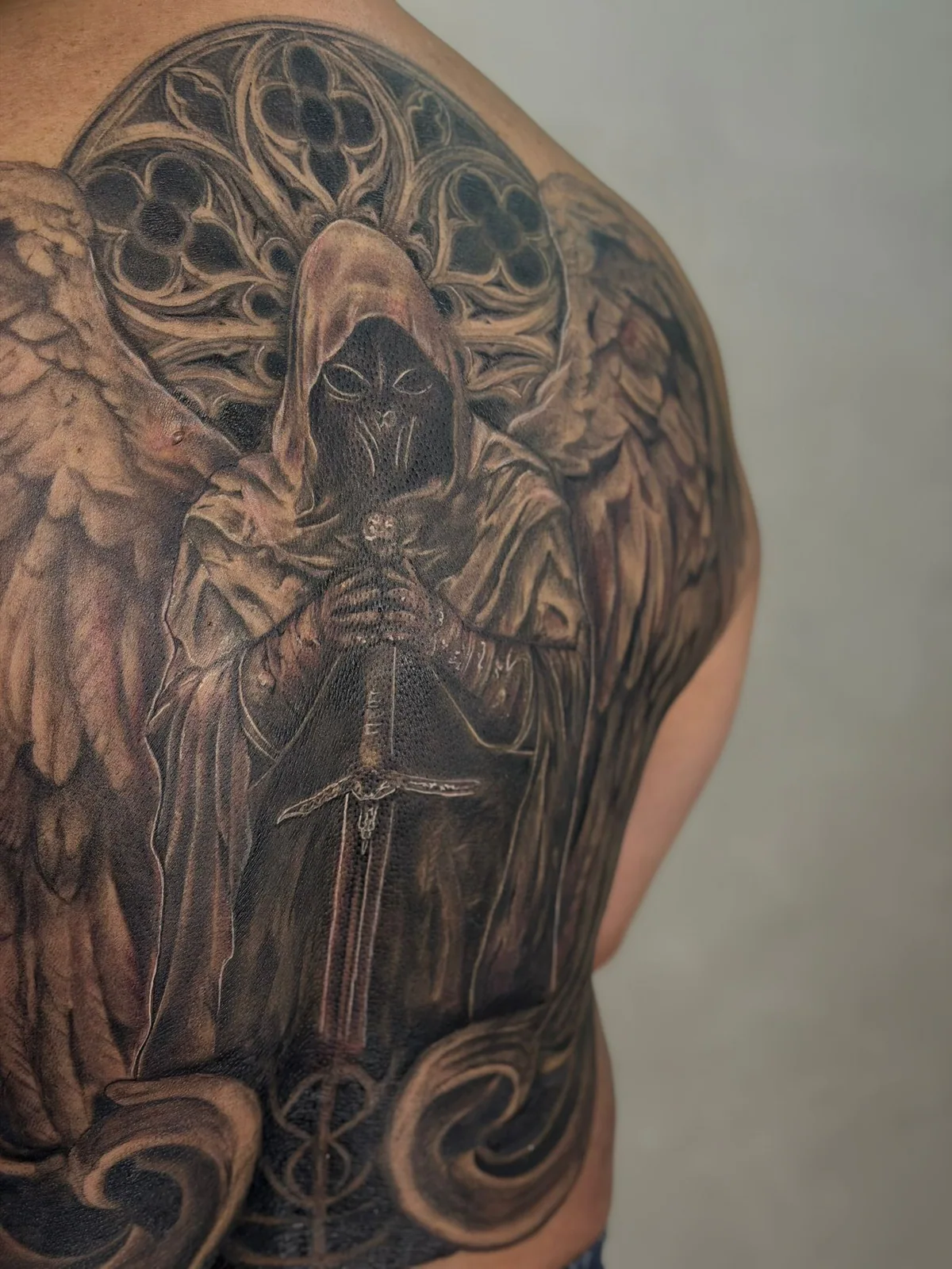 Black-and-grey full-back winged guardian tattoo by HIM
