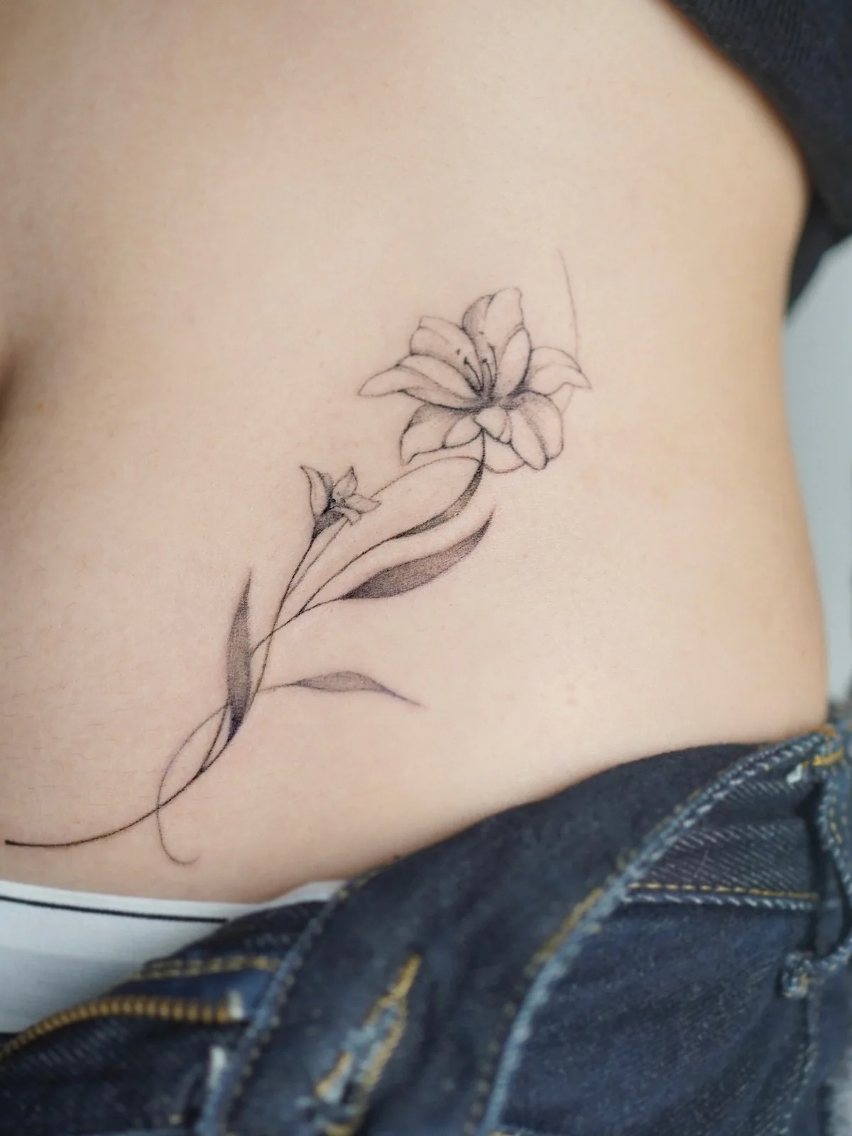 Fine-line waist floral tattoo by Moon