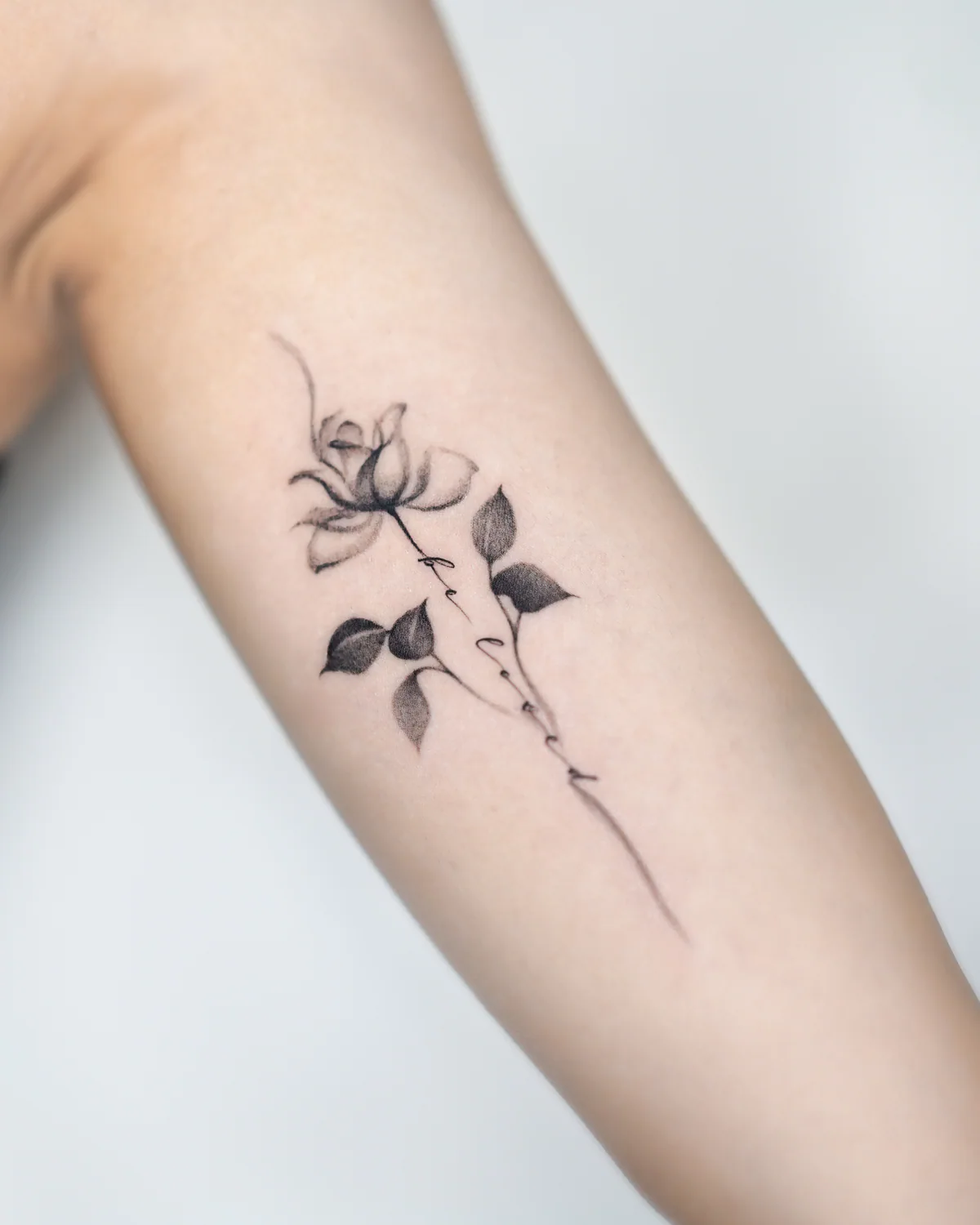 Fine-line rose and lettering tattoo by Moon